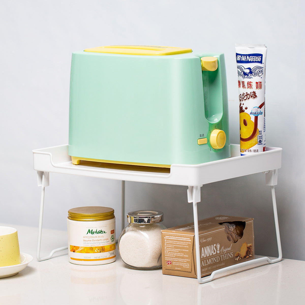 Small green and yellow toaster on a white smart storage rack (stand) with various items around it.